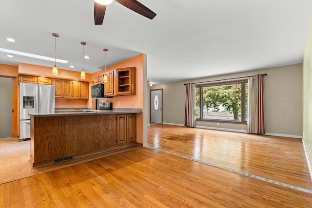 1635 N 21st St, Manitowoc, WI 54220 - kitchen featuring stainless steel fridge, black microwave, brown cabinetry, light wood-style floors, and a peninsula