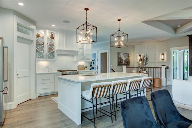 6649 Hope Ln, Eau Claire, WI 54701 - kitchen with light countertops, backsplash, white cabinets, light wood-type flooring, and stove