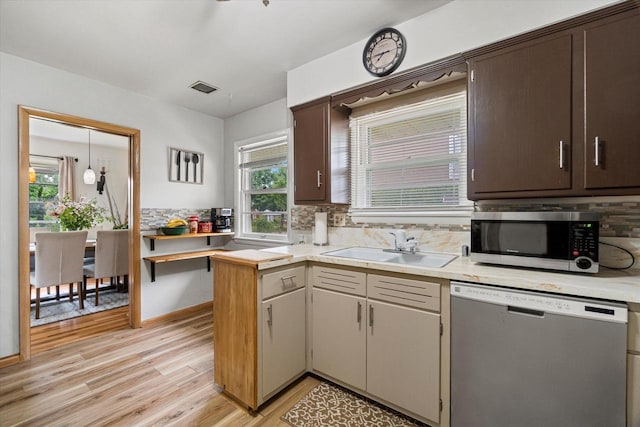 9230 W Auer Ave, Milwaukee, WI 53222 - kitchen featuring appliances with stainless steel finishes, light wood-type flooring, light countertops, decorative backsplash, and a peninsula