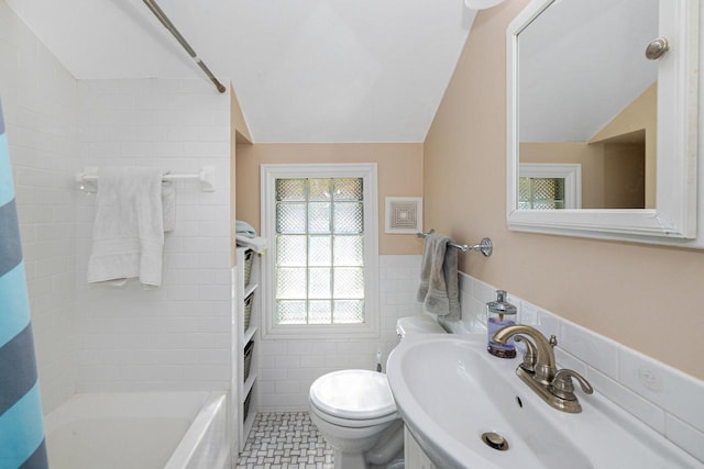 1441 N 66th St, Wauwatosa, WI 53213 - full bathroom featuring tile walls, lofted ceiling, shower / bathtub combination with curtain, tile patterned floors, and a wainscoted wall