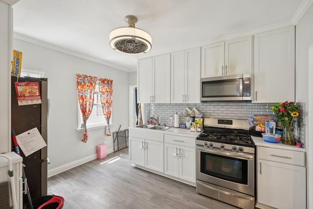 3936 N 14th St Unit 3938, Milwaukee, WI 53206 - kitchen featuring appliances with stainless steel finishes, backsplash, light countertops, ornamental molding, and white cabinetry