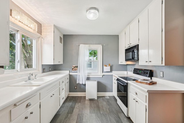 509 S 6th Ave, West Bend, WI 53095 - kitchen with range with electric cooktop, black microwave, dark wood-style floors, white cabinetry, and light countertops