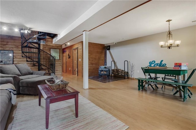 5683N Ham-Holly Dr, Stone Lake, WI 54876 - living room featuring a wood stove, stairs, light wood-style flooring, wood walls, and a chandelier
