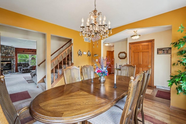8216 Anna Ave, Wind Lake, WI 53185 - dining space featuring stairs, a chandelier, a stone fireplace, and wood finished floors