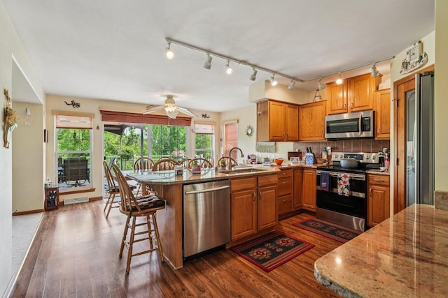 8216 Anna Ave, Wind Lake, WI 53185 - kitchen featuring stainless steel appliances, dark wood-style floors, a peninsula, and brown cabinetry