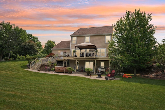8216 Anna Ave, Wind Lake, WI 53185 - back of property at dusk featuring a hot tub, a wooden deck, a patio area, a lawn, and stairs