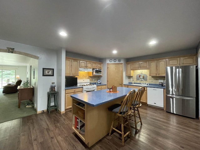 1216 Pond View Cir, De Pere, WI 54115 - kitchen with white appliances, a kitchen island, under cabinet range hood, dark countertops, and dark wood-style floors