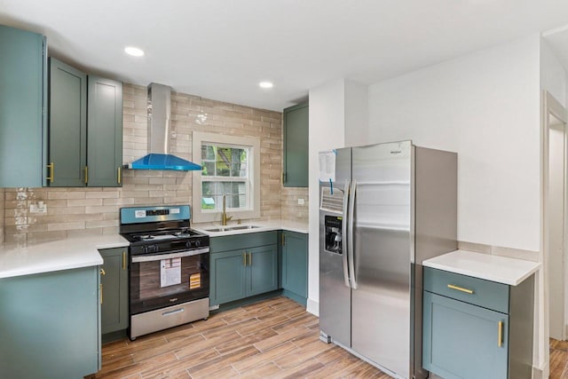 1617 69th St, Kenosha, WI 53143 - kitchen featuring appliances with stainless steel finishes, wall chimney exhaust hood, green cabinets, light wood-style flooring, and recessed lighting