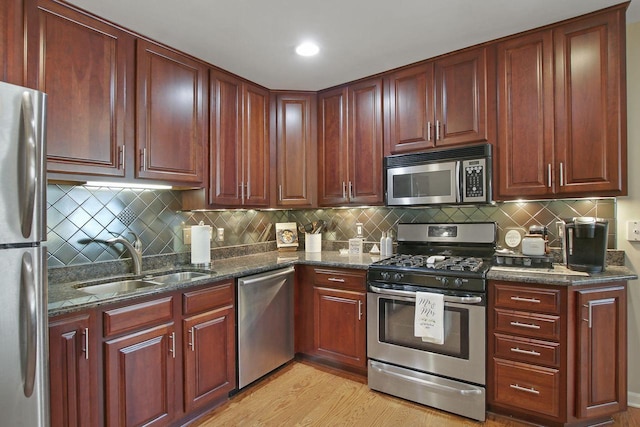 408 55th St Unit B, Kenosha, WI 53140 - kitchen featuring appliances with stainless steel finishes, decorative backsplash, light wood-type flooring, and dark stone counters