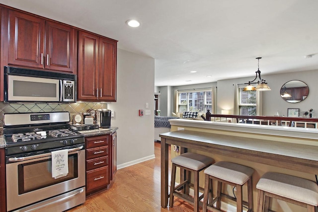 408 55th St Unit B, Kenosha, WI 53140 - kitchen featuring stainless steel appliances, dark brown cabinets, a breakfast bar area, backsplash, and light wood-style floors