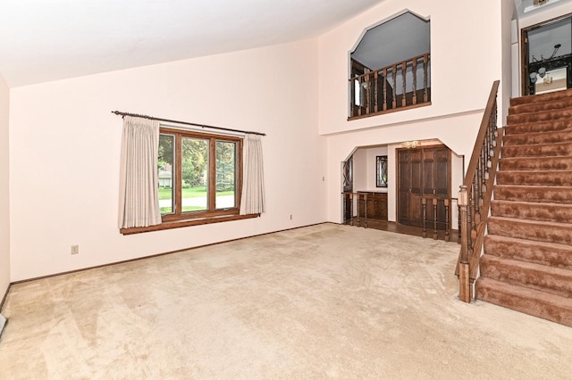 7701 W Coventry Dr, Franklin, WI 53132 - unfurnished living room with carpet flooring, high vaulted ceiling, and stairs