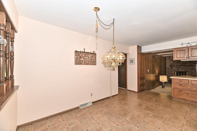 7701 W Coventry Dr, Franklin, WI 53132 - kitchen featuring a brick fireplace, light countertops, brown cabinetry, a chandelier, and decorative light fixtures
