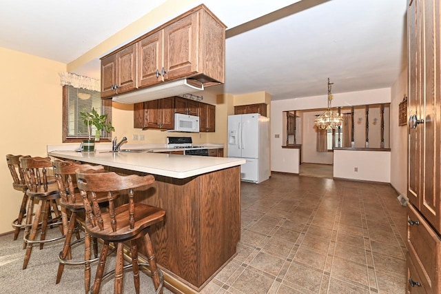 7701 W Coventry Dr, Franklin, WI 53132 - kitchen featuring white appliances, a peninsula, a chandelier, a kitchen bar, and light countertops