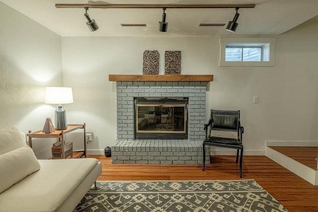 5717 Cedar Ridge Rd, Middleton, WI 53562 - living room featuring rail lighting, wood finished floors, and a brick fireplace