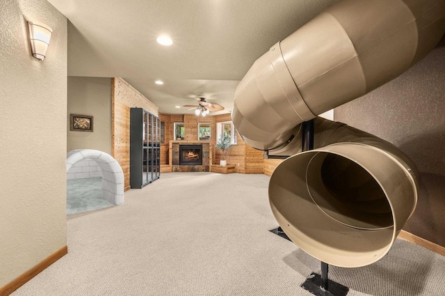 1022 Cortland Ln, Stevens Point, WI 54482 - carpeted living room featuring a textured wall, a ceiling fan, a warm lit fireplace, recessed lighting, and wooden walls