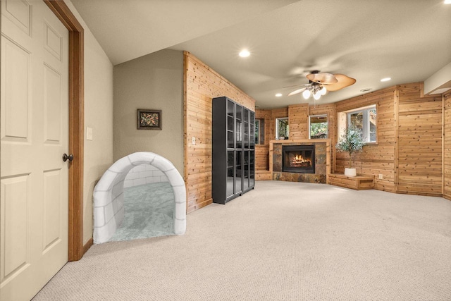 1022 Cortland Ln, Stevens Point, WI 54482 - unfurnished living room featuring carpet, wood walls, ceiling fan, a stone fireplace, and recessed lighting