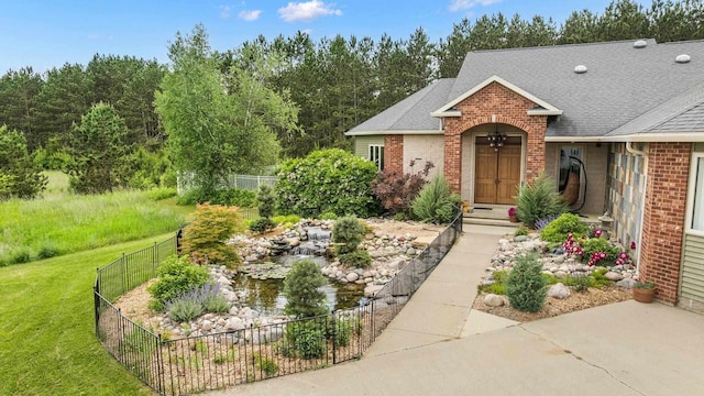 1022 Cortland Ln, Stevens Point, WI 54482 - view of front facade featuring brick siding, roof with shingles, a fenced backyard, and a garden pond