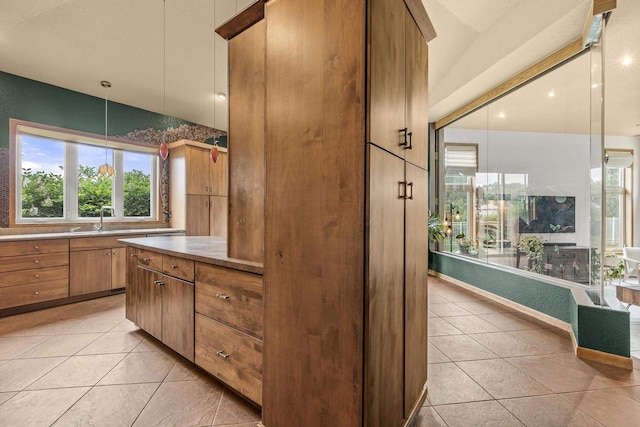 1022 Cortland Ln, Stevens Point, WI 54482 - kitchen featuring plenty of natural light, brown cabinetry, light tile patterned floors, and light countertops