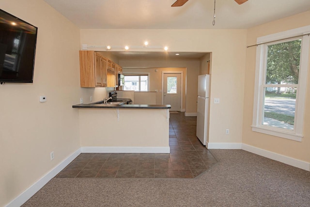 604 Wilson St, Winona, MN 55987 - kitchen featuring freestanding refrigerator, a peninsula, a ceiling fan, and dark colored carpet
