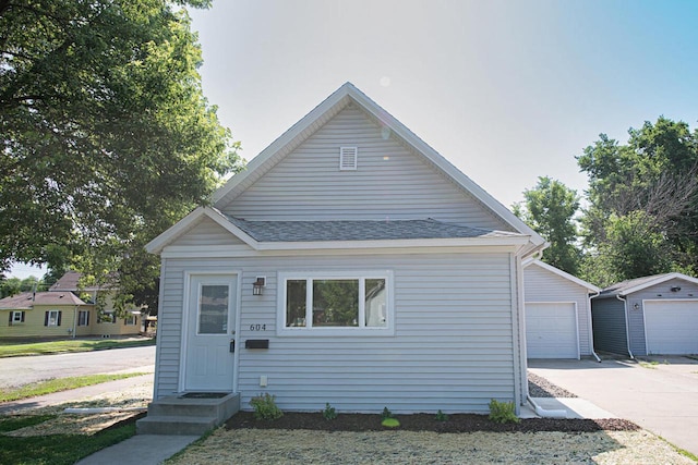 604 Wilson St, Winona, MN 55987 - view of front facade with an outdoor structure, roof with shingles, concrete driveway, and a garage