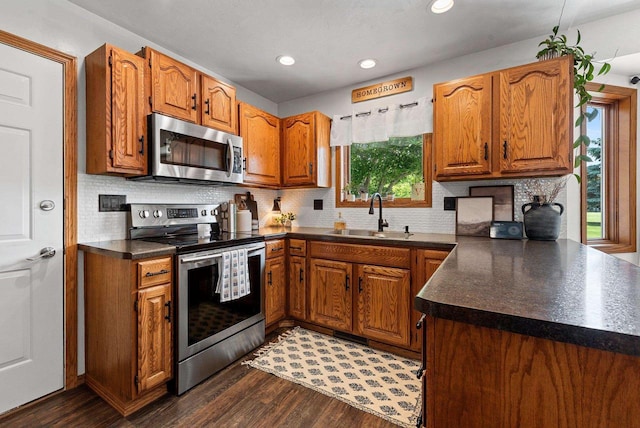 4814 Placid Way, New Franken, WI 54229 - kitchen with stainless steel appliances, dark countertops, brown cabinetry, dark wood-style floors, and decorative backsplash