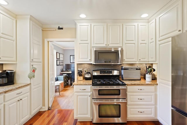 511 Wisconsin River Dr, Port Edwards, WI 54469 - kitchen with stainless steel appliances, crown molding, tasteful backsplash, light wood-style flooring, and white cabinetry