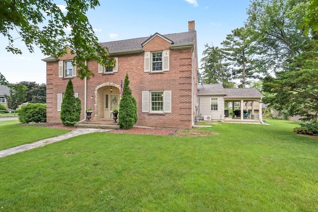 511 Wisconsin River Dr, Port Edwards, WI 54469 - colonial-style house featuring a chimney, a front yard, and brick siding