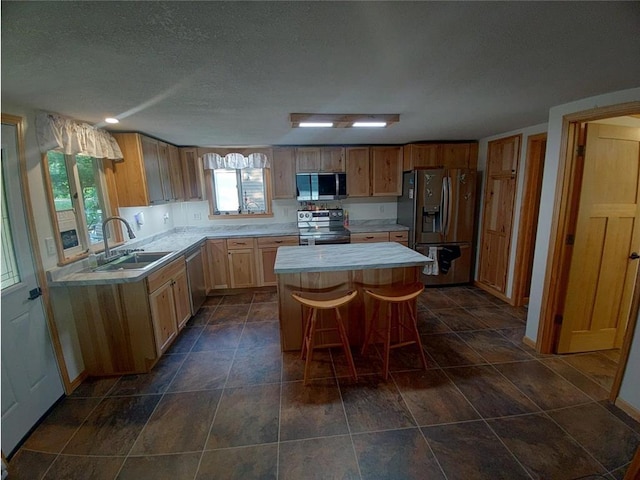 1959 79th St, Balsam Lake, WI 54853 - kitchen featuring appliances with stainless steel finishes, light countertops, a center island, healthy amount of natural light, and a textured ceiling