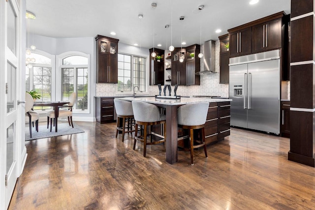 W1977 Center Valley Rd, Kaukauna, WI 54130 - kitchen with built in refrigerator, wall chimney range hood, light countertops, dark brown cabinetry, and dark wood-type flooring