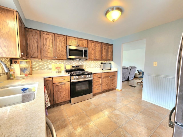 1239 Columbus Ave, Sheboygan, WI 53083 - kitchen with stainless steel appliances, tasteful backsplash, light countertops, and brown cabinetry