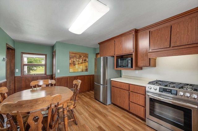 243 Chicago St, Pulaski, WI 54162 - kitchen featuring appliances with stainless steel finishes, a wainscoted wall, wood walls, brown cabinetry, and light countertops