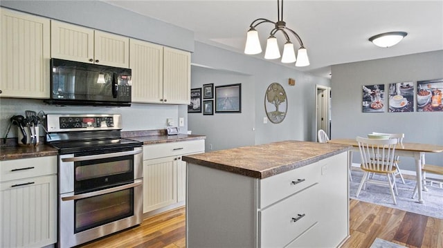 12901 7th St, Osseo, WI 54758 - kitchen featuring range with two ovens, black microwave, light wood-type flooring, a kitchen island, and dark countertops