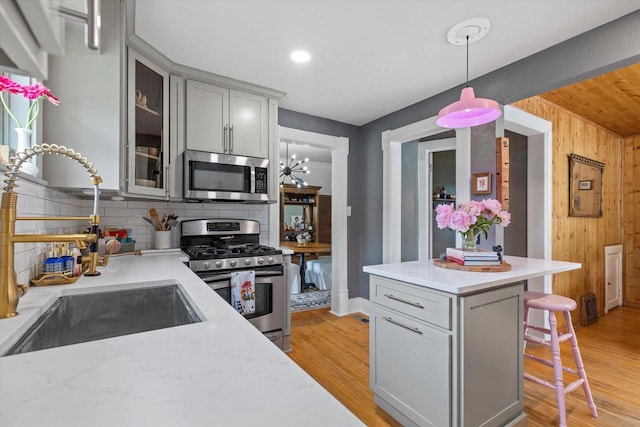 128 Maple Ave, Hartland, WI 53029 - kitchen with stainless steel appliances, gray cabinets, decorative backsplash, a kitchen breakfast bar, and glass insert cabinets