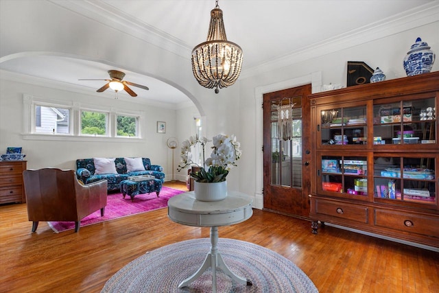 128 Maple Ave, Hartland, WI 53029 - living area with arched walkways, ornamental molding, wood finished floors, ceiling fan, and a chandelier