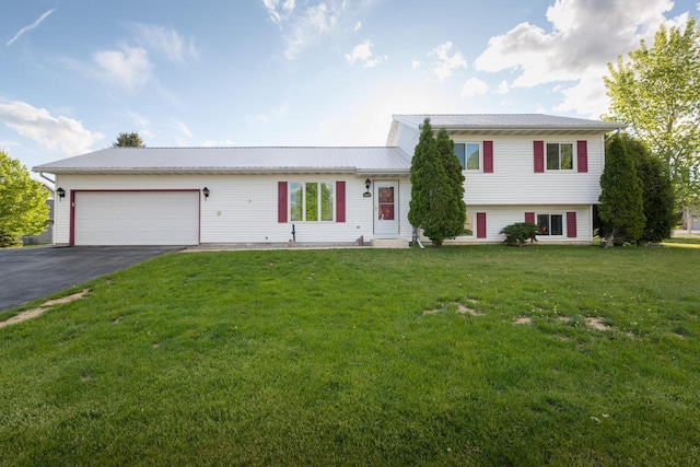 123 Westgate Dr, Iron Ridge, WI 53035 - tri-level home featuring an attached garage, asphalt driveway, a front lawn, and a metal roof