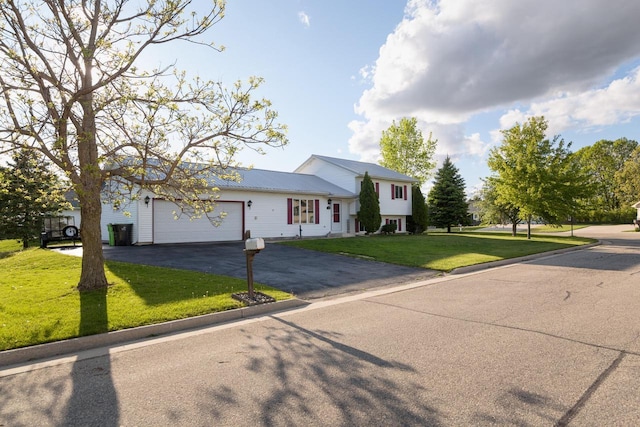 123 Westgate Dr, Iron Ridge, WI 53035 - tri-level home featuring asphalt driveway, a garage, a front lawn, and a metal roof