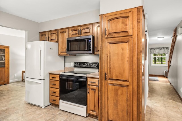 2311 Maplewood Dr, Plover, WI 54467 - kitchen with stainless steel microwave, range with electric cooktop, freestanding refrigerator, and brown cabinets