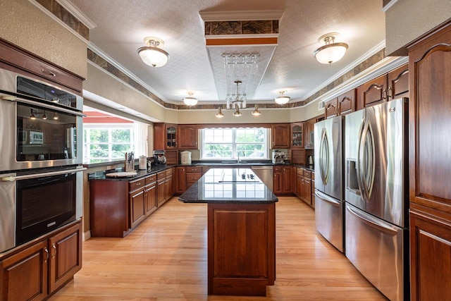 N2194 Valley Rd, La Crosse, WI 54601 - kitchen with stainless steel appliances, a center island, light wood-style flooring, a textured ceiling, and crown molding