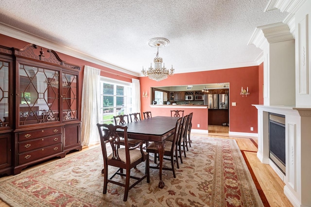 N2194 Valley Rd, La Crosse, WI 54601 - dining room with ornamental molding, a chandelier, light wood-style flooring, a textured ceiling, and a fireplace