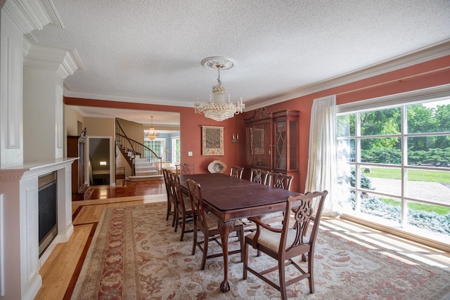 N2194 Valley Rd, La Crosse, WI 54601 - dining space with a chandelier, stairs, crown molding, a textured ceiling, and a fireplace