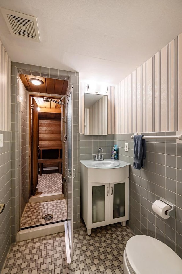 N2194 Valley Rd, La Crosse, WI 54601 - full bath with tile walls, wallpapered walls, vanity, wainscoting, and a stall shower