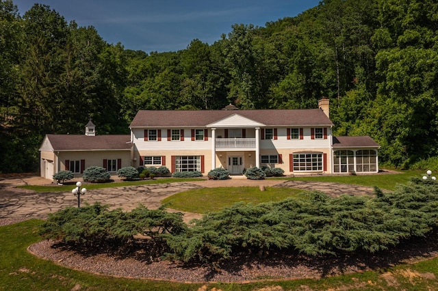 N2194 Valley Rd, La Crosse, WI 54601 - view of front of house featuring a balcony, a forest view, a sunroom, a chimney, and an attached garage