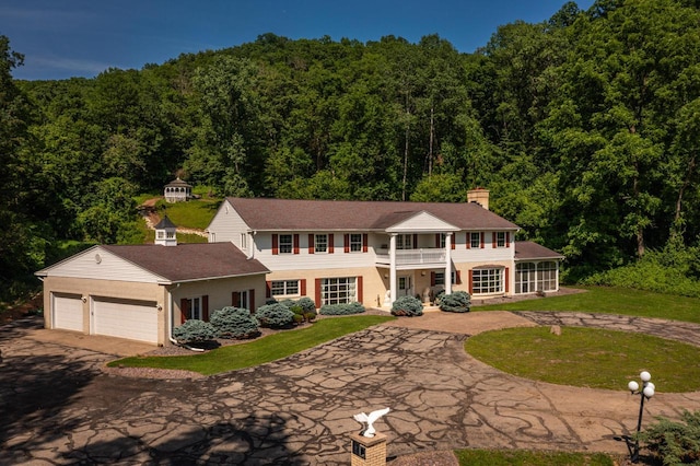 N2194 Valley Rd, La Crosse, WI 54601 - view of front of property featuring driveway, a forest view, a balcony, a front lawn, and a garage