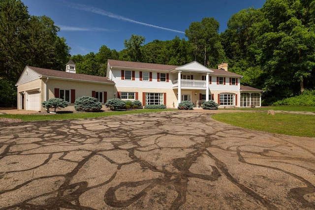 N2194 Valley Rd, La Crosse, WI 54601 - greek revival inspired property with a balcony, concrete driveway, an attached garage, a chimney, and a front lawn