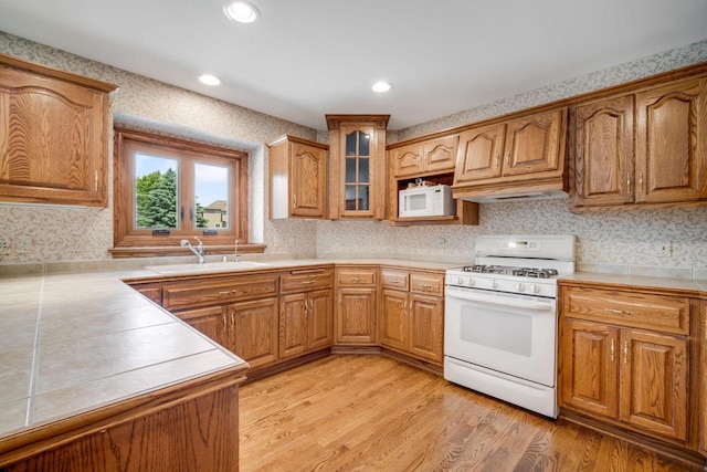 N65W38340 S Woodlake Cir, Oconomowoc, WI 53066 - kitchen featuring white appliances, wallpapered walls, brown cabinets, light wood finished floors, and glass insert cabinets