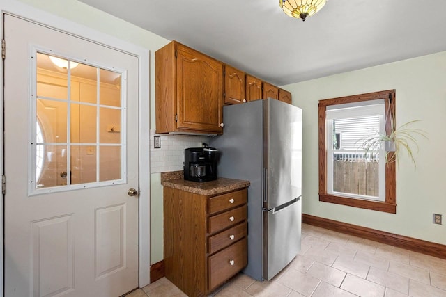 931 Carney Blvd, Marinette, WI 54143 - kitchen with freestanding refrigerator, brown cabinets, light tile patterned floors, tasteful backsplash, and dark countertops