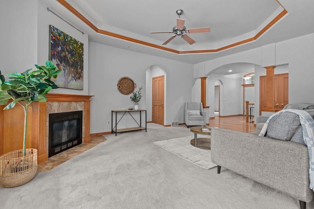 2506 Waterford Ct, Neenah, WI 54956 - carpeted living room featuring arched walkways, a raised ceiling, ceiling fan, and a tiled fireplace