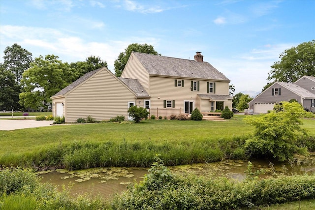 10800 N Norway Dr, Mequon, WI 53092 - back of property featuring a chimney, a yard, driveway, and a garage