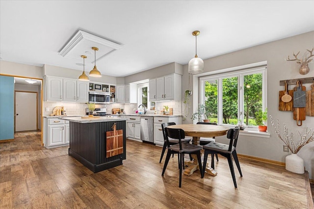 1021 Aspen Pl, West Bend, WI 53095 - kitchen featuring stainless steel appliances, white cabinets, light countertops, tasteful backsplash, and a kitchen island