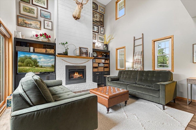 1021 Aspen Pl, West Bend, WI 53095 - living area with wood finished floors, a brick fireplace, and a high ceiling